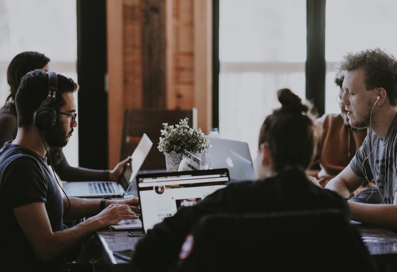 a group of people sitting around a table with a laptop