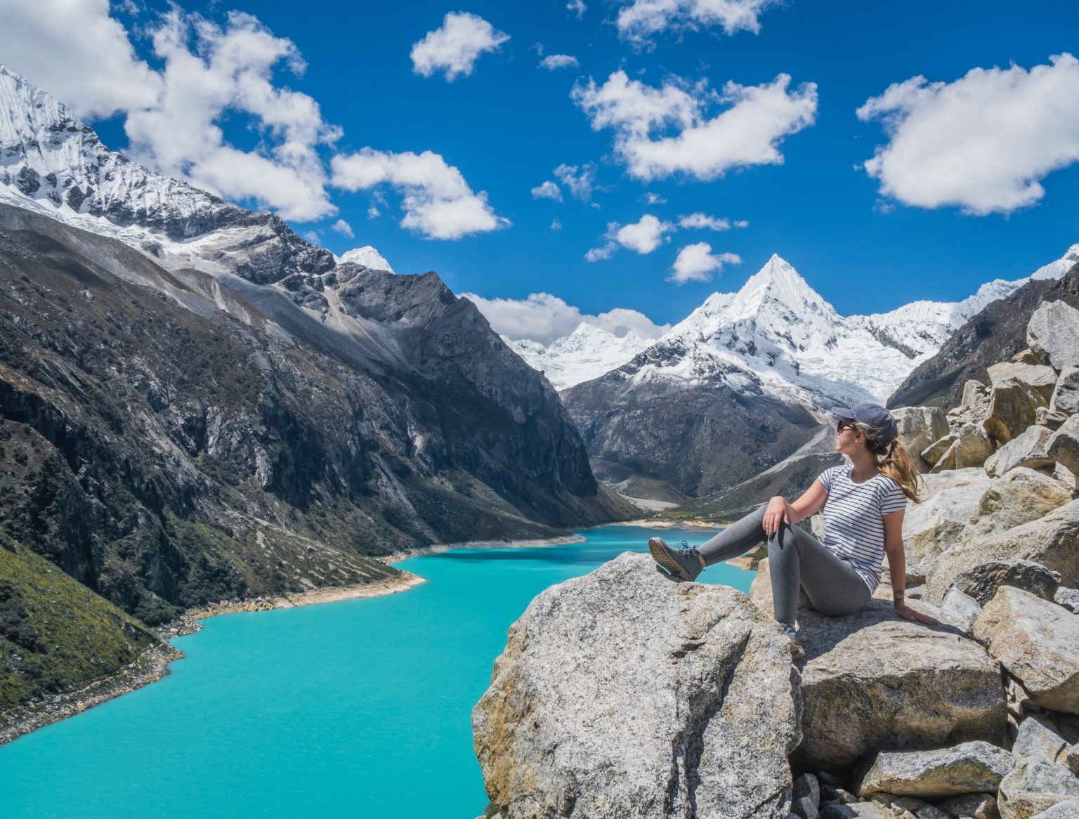 a man sitting on a rock near a river and mountains