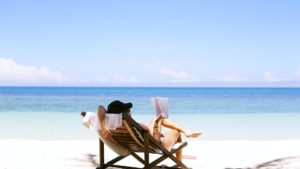 a couple of people sitting in chairs on a beach