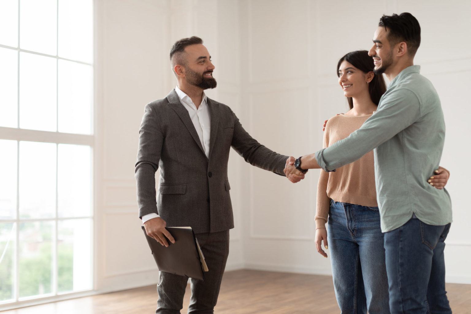 Couple Buying New Apartment, Shaking Hands With Realtor